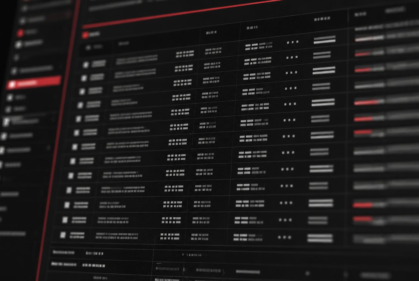 Close-up of a dark software dashboard showing dense data rows with red status indicators